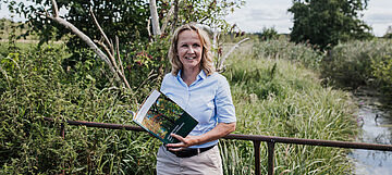 Steffi Lemke blättert durch das Aktionsprogramm Natürlicher Klimaschutz