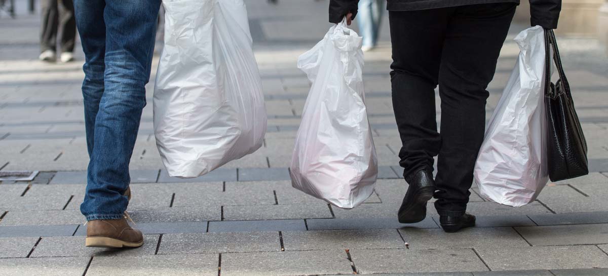 Personen spazieren mit ihrem Einkauf in Plastiktüten