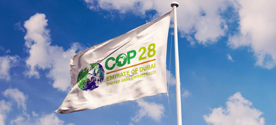 Flagge mit COP28-Logo vor blauem Himmel