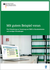 Management and Audit Scheme, kurz EMAS. Im Hintergrund des Büros steht ein Schrank mit grünen Aktenordnern.