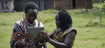 Zwei Frauen einer traditionellen Maasai-Gemeinschaft mit einem iPad inder hand.