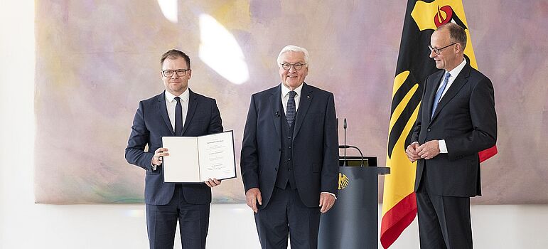 Carsten Schneider mit Ernennungsurkunde neben Bundespräsident Frank-Walter Steinmeier und Bundeskanzler Friedrich Merz 
