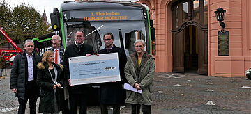Mainzer Mobilität Florian Pronold steht mit Vertretern der Stadt Mainz vor einem Elektrobus mit den Förderbescheid in der Hand. Weitere Informationen siehe Bildunterschrift