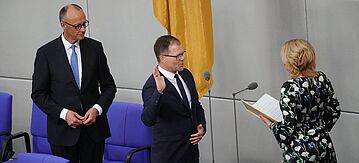 Carsten Schneider bei der Vereidigung im Bundestag mit Bundestagspräsidentin Julia Klöckner und Bundeskanzler Friedrich Merz 