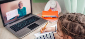 Mädchen lernt online mit ihren Laptop und sieht ihrer Lehrerin auf dem Bildschirm