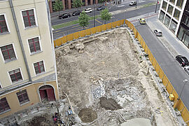 Blick aus der Vogelperspektive auf eine umzäunte Baustelle kurz nach Beginn der Aushubarbeiten.