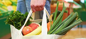Mann trägt volle Tasche mit Obst und Gemüse im Supermarkt