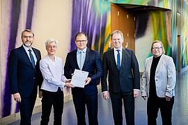Bundesumweltminister Carsten Schneider (M) nimmt das Gutachten des Expertenrats für Klimafragen entgegen.