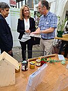 Die Bundesumweltministerin und die Besucher informieren sich über regionalen Honig. 