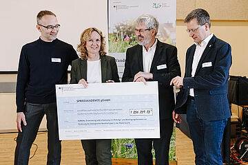 Steffi Lemke und der brandenburgische Umweltminister Axel Vogel übergeben einen Förderscheck.