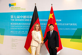 Steffi Lemkes und Herr Huang RunQiu schütteln sich die Hand vor einer Fotowand